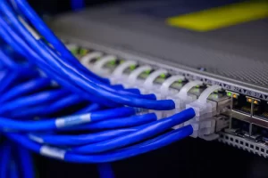 Close-up of blue Ethernet cables connected to a network switch, indicating a structured cabling system used in professional IT infrastructure setups.